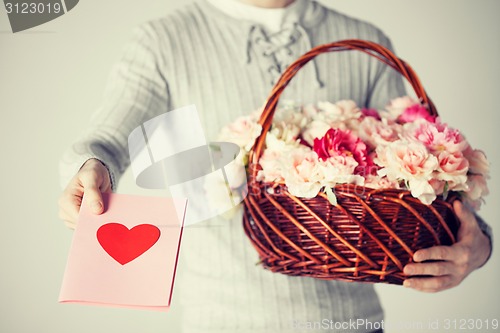 Image of man holding basket full of flowers and postcard