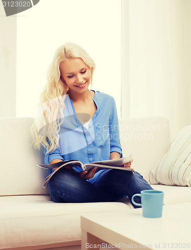 Image of woman with cup of coffee reading magazine at home