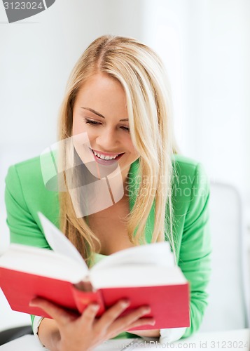 Image of smiling young woman reading book at school