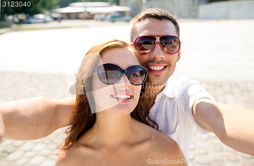 Image of smiling couple wearing sunglasses making selfie