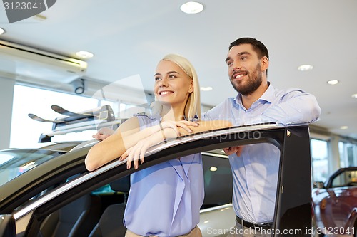 Image of happy couple buying car in auto show or salon