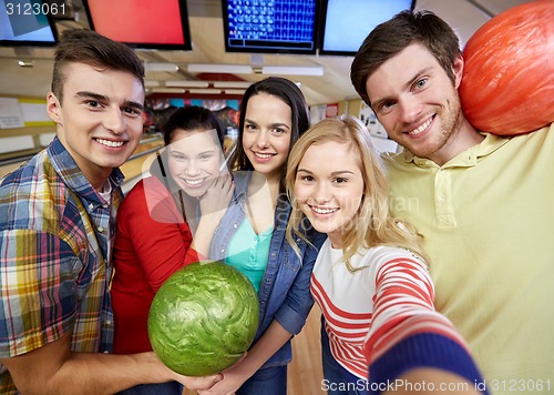 Image of happy friends taking selfie in bowling club