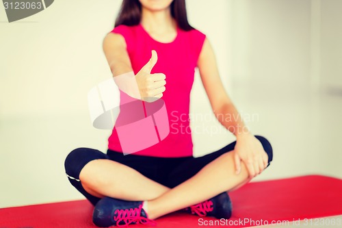 Image of girl sitting in lotus position with thumbs up