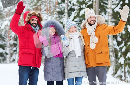 Image of group of friends waving hands in winter forest