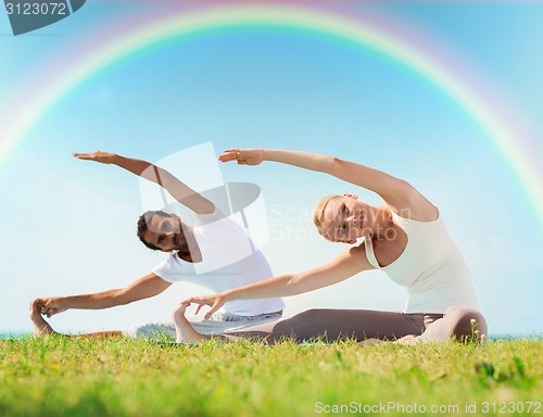 Image of happy couple stretching and doing yoga exercises