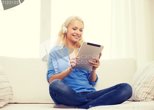 Image of woman with tablet pc and headphones at home