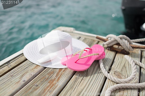 Image of close up of hat, sunscreen and slippers at seaside