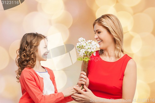 Image of happy little daughter giving flowers to her mother
