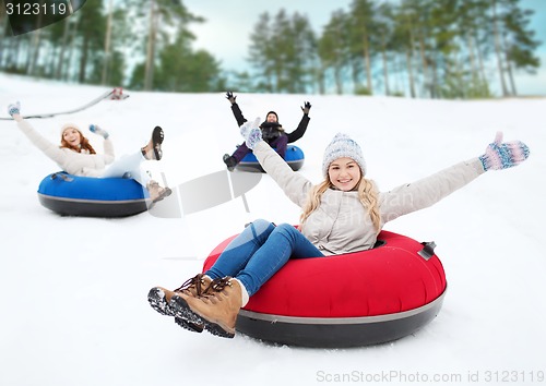 Image of group of happy friends sliding down on snow tubes