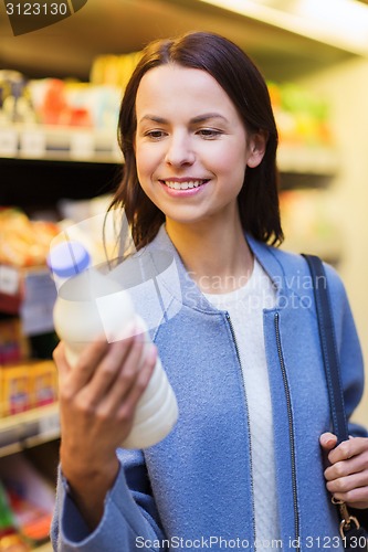 Image of happy woman holding milk bottle in market