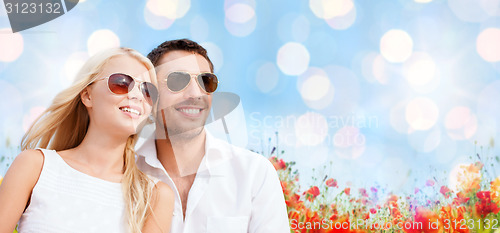 Image of happy couple in shades over poppy field background