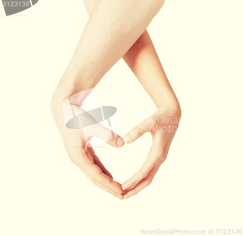 Image of woman and man hands showing heart shape