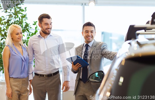 Image of happy couple with car dealer in auto show or salon