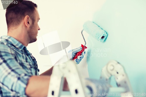 Image of close up of male in gloves holding painting roller