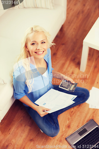 Image of smiling woman with papers, laptop and calculator