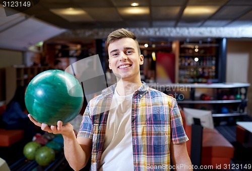 Image of happy young man holding ball in bowling club