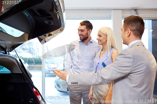 Image of happy couple with car dealer in auto show or salon