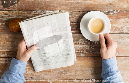 Image of close up of male hands with newspaper and coffee