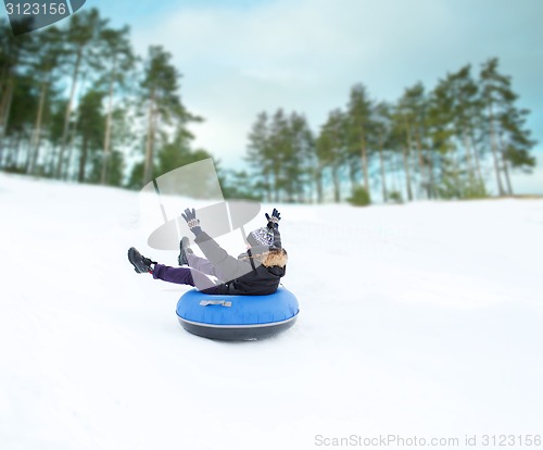 Image of happy young man sliding down on snow tube