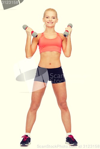 Image of smiling beautiful sporty woman with dumbbells