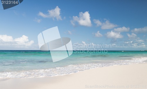 Image of blue sea or ocean, white sand and sky with clouds
