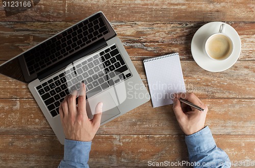 Image of close up of male hands with laptop and notebook