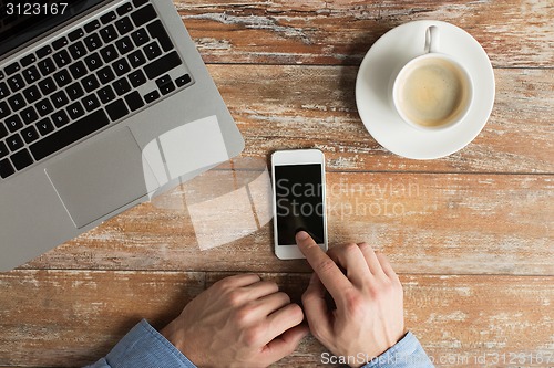 Image of close up of hands with laptop and smartphone