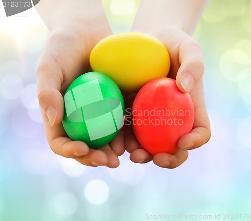 Image of close up of kid hands holding colored eggs