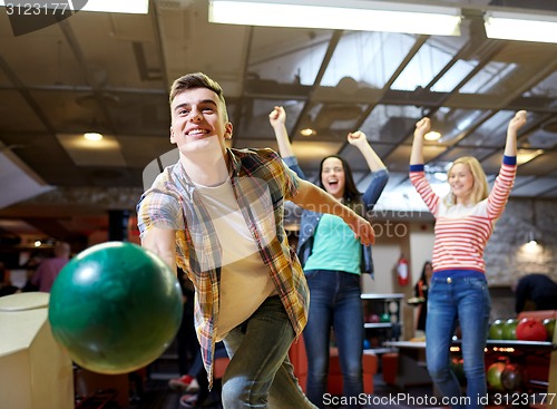 Image of happy young man throwing ball in bowling club