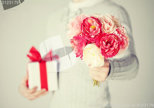 Image of man holding bouquet of flowers and gift box