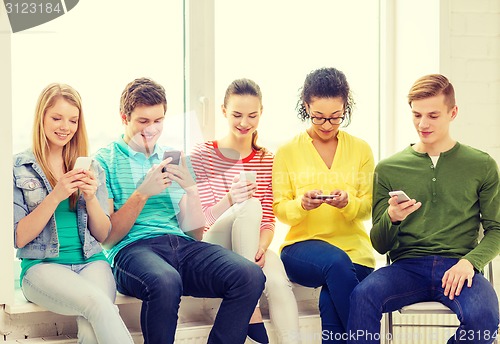 Image of smiling students with smartphone texting at school