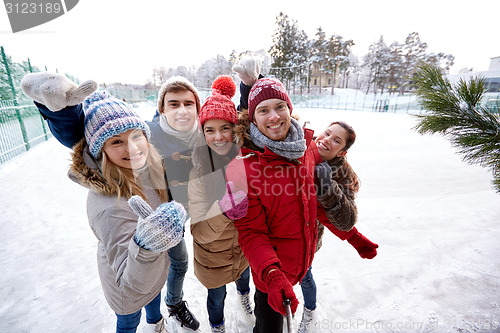 Image of happy friends with smartphone on ice skating rink