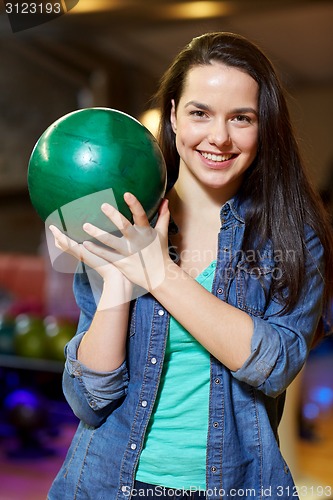 Image of happy young woman holding ball in bowling club