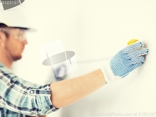 Image of architect measuring wall with flexible ruler