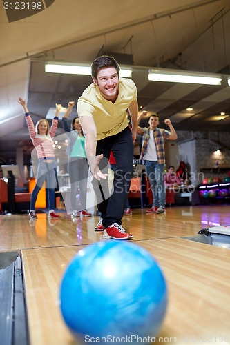 Image of happy young man throwing ball in bowling club