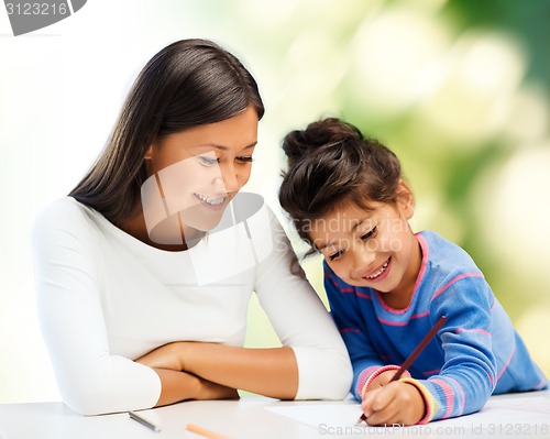 Image of happy mother and daughter drawing with pencils