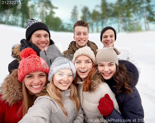 Image of group of smiling friends taking selfie outdoors