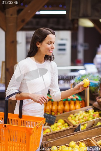 Image of happy young woman with food basket in market