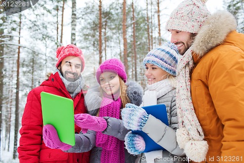 Image of smiling friends with tablet pc in winter forest