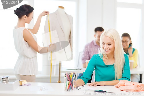 Image of smiling fashion designers working in office