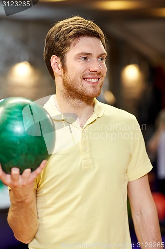 Image of happy young man holding ball in bowling club