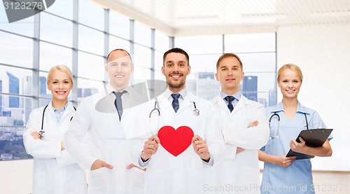 Image of happy young doctors cardiologists with red heart