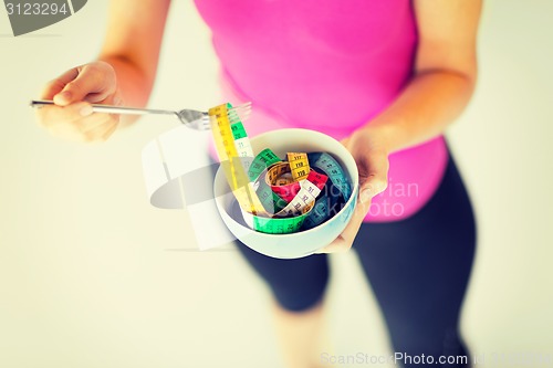 Image of woman hands holding bowl with measuring tape