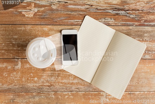 Image of close up of notebook, coffee cup and smartphone