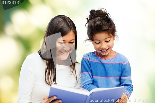 Image of happy mother and little daughter reading book