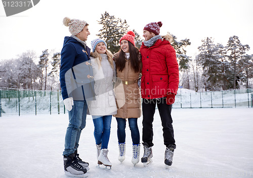 Image of happy friends ice skating on rink outdoors