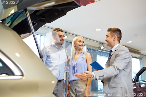 Image of happy couple with car dealer in auto show or salon