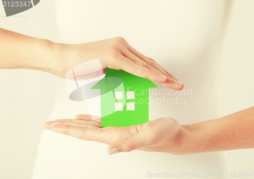 Image of woman hands holding green house