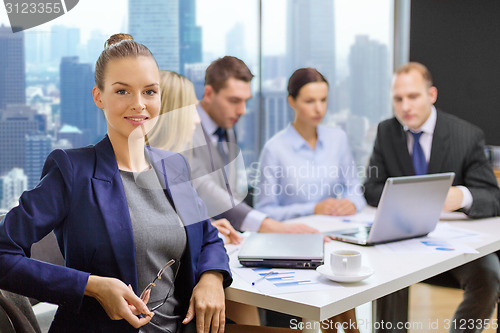 Image of businesswoman over business team in office