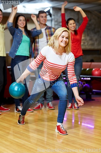 Image of happy young woman throwing ball in bowling club
